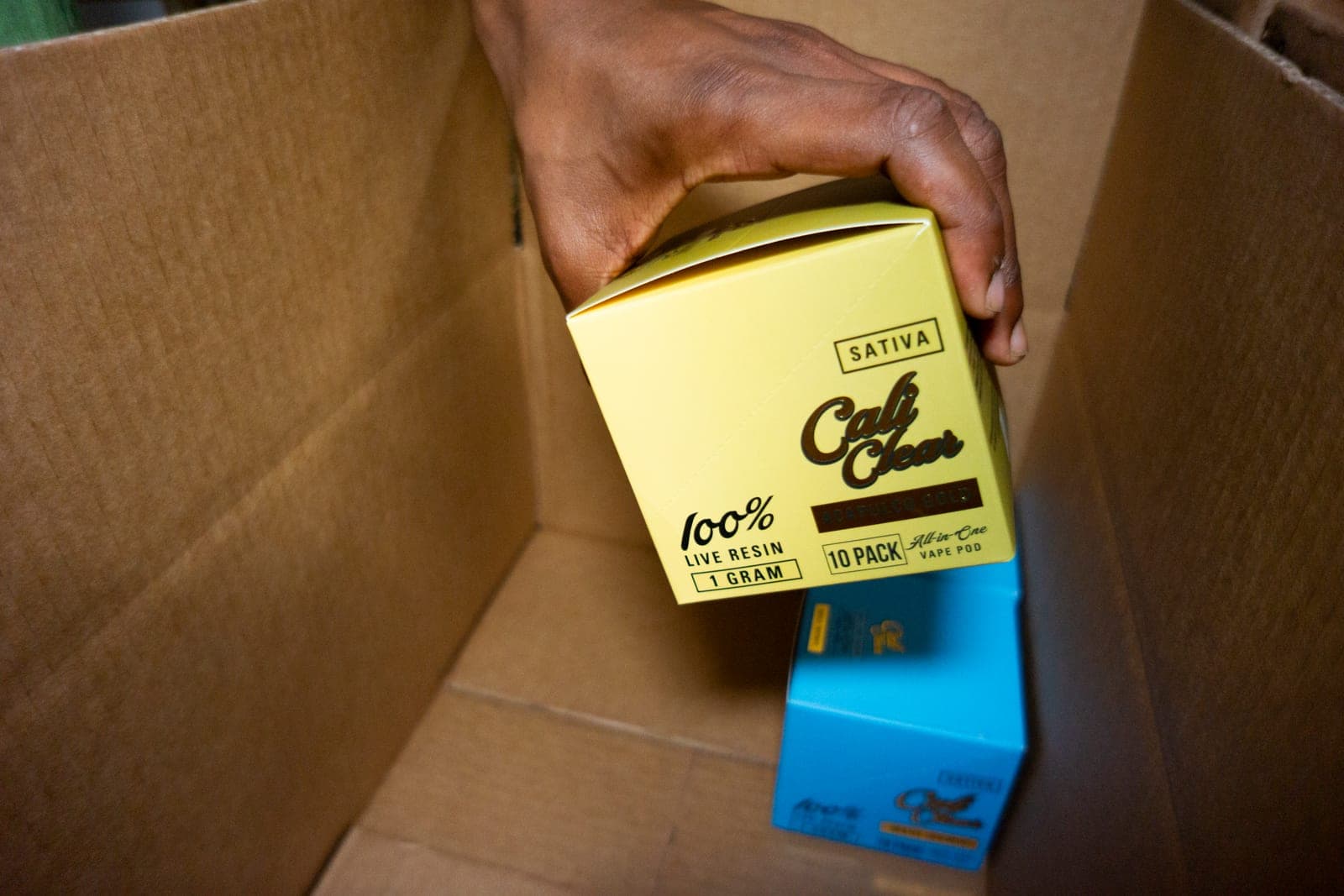 Operator packing Cali Clear live resin vape cases into a shipping box for a wholesale order